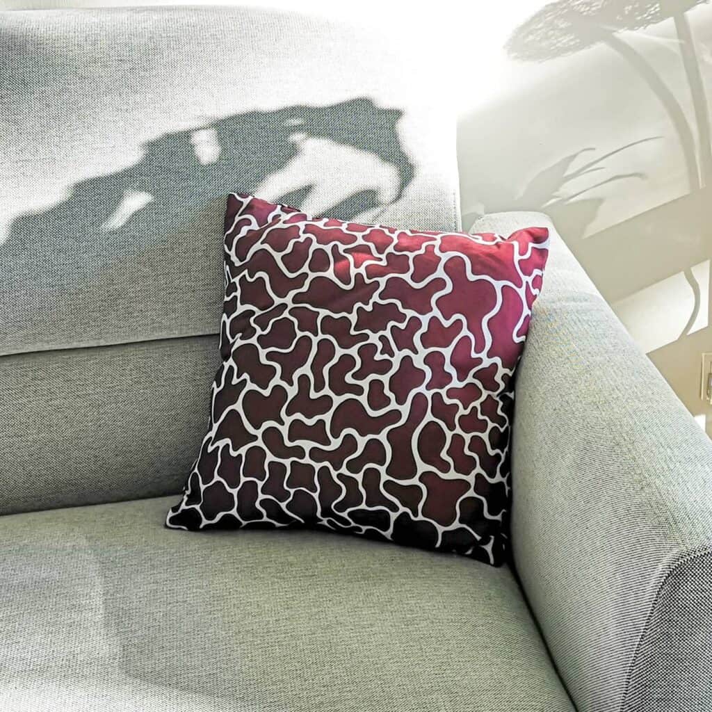 Magenta cushion with soft pattern on grey couch and dappled sunlight