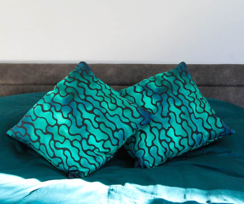 Two cushions with wavey green and dark blue pattern on black background