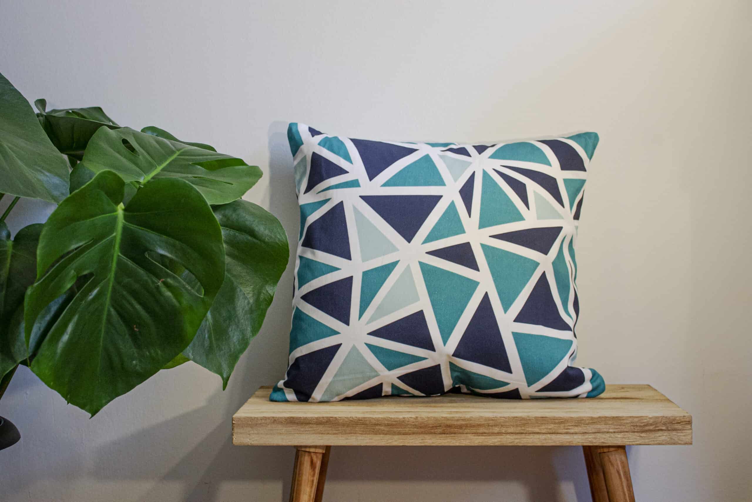 Geometric Throw Cushion Blue and Midnight blue Triangle Pattern Design on a bench with a plant