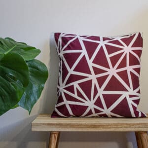 Bright red throw cushion wine geometric design on a bench with plant